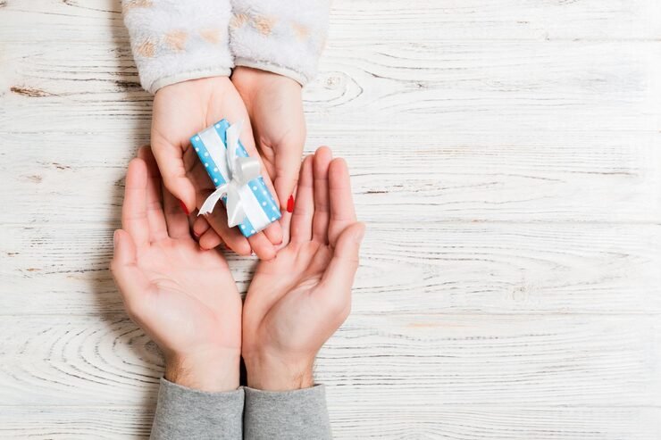 top-view-gift-box-hand-give-present-concept-wooden-background_1048944-17090325